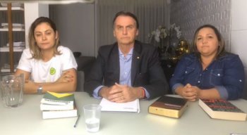 Jair Bolsonaro ao lado da esposa e de uma intérprete de libras