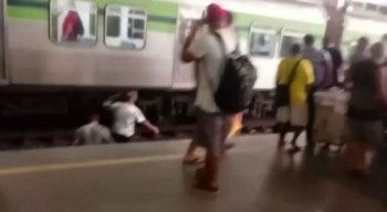 Passageiros passam perto de trem em movimento