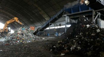 Por meio de guindastes, o material é jogado em uma gigantesca máquina trituradora, de onde sai a primeira mistura