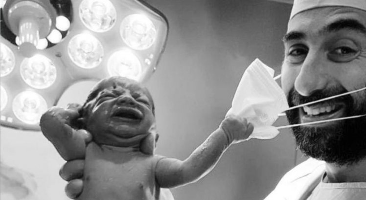 Bebê puxa máscara de obstetra na sala de parto