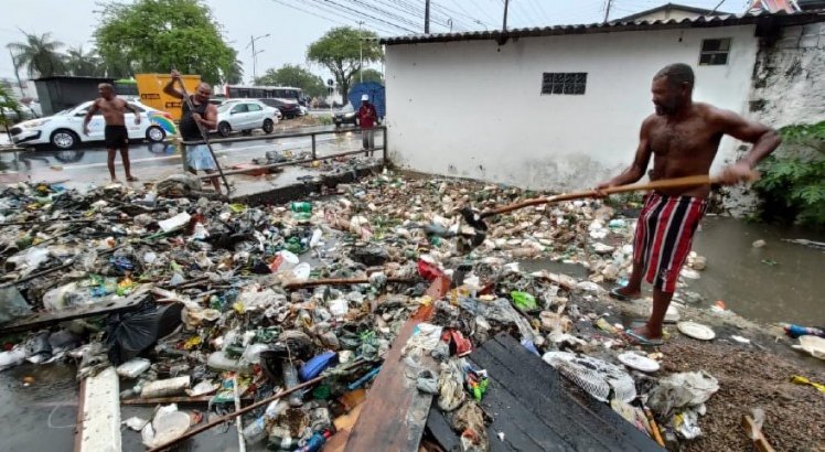 Moradores tentam tirar lixo de canal