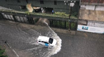 Táxi passa com dificuldade por rua alagada nas Graças, Zona Norte