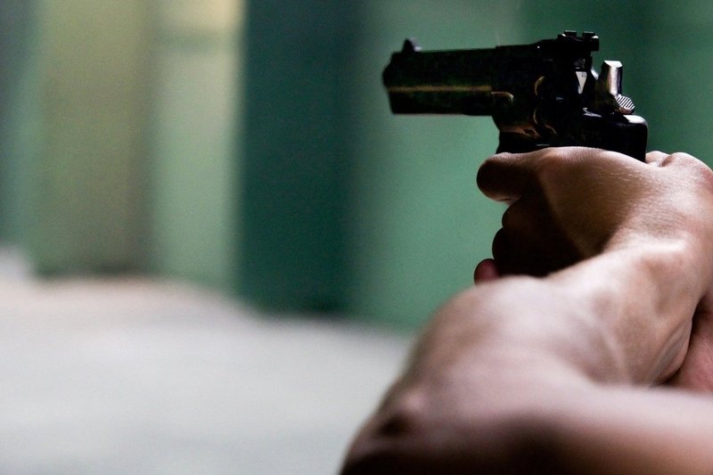 Imagem ilustrativa de pessoa segurando arma