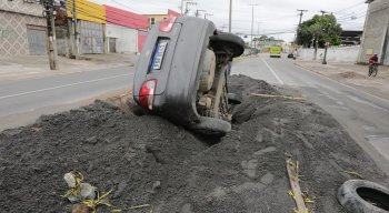 carro, um automóvel de passeio, ficou totalmente caído no buraco, apenas as rodas traseiras ficaram visíveis.