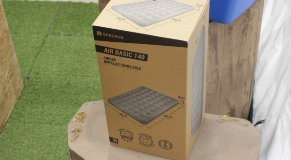 Caixa de uma cama de casal inflável em cima de um toco de madeira.