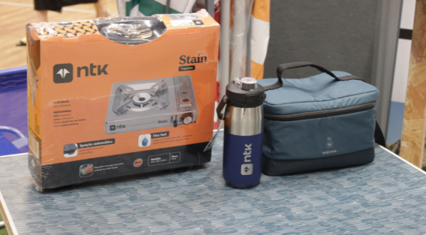 Caixa de fogareiro, garrafa e bolsa térmica em uma mesa.