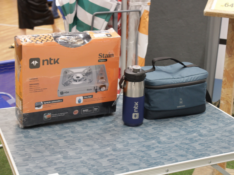 Caixa de fogareiro, garrafa e bolsa térmica em uma mesa.