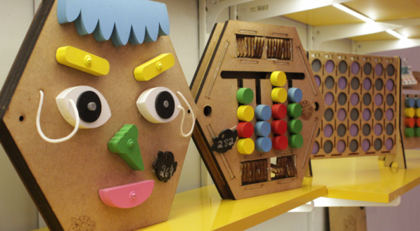 Brinquedos educativos coloridos em uma prateleira amarela.