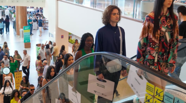 Modelos descem uma escada rolante. Eles vestem roupas coloridas e casuais de primavera/ver&atilde;o.