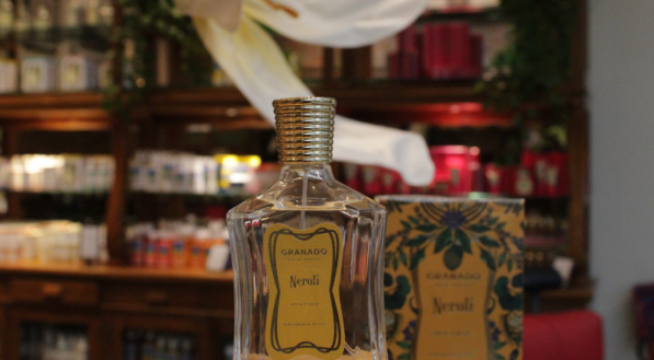A imagem mostra o perfume  "Neroli" da Granado, exibido sobre um pedestal em uma loja, com sua caixa decorada ao fundo.