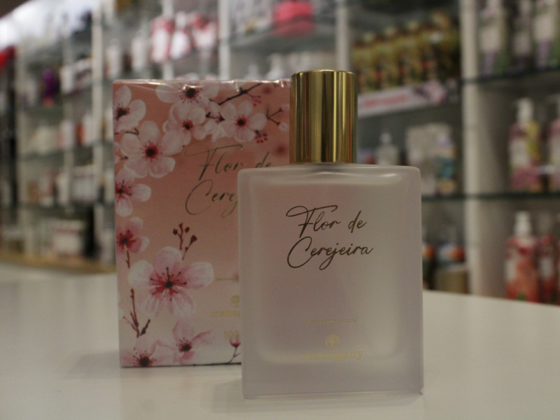 A imagem mostra o perfume "Flor de Cerejeira" da Mahogany, com sua embalagem que tem estampa de flores ao fundo. 