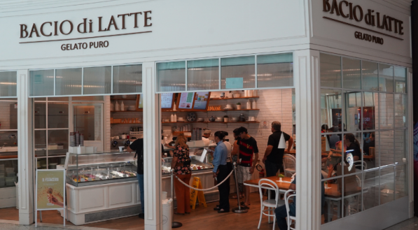 A imagem mostra a fachada da Bacio di Latte, com um design limpo e elegante em branco.