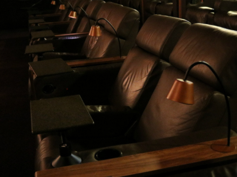 Detalhe de poltronas de cinema VIP/Prime em couro marrom escuro.
