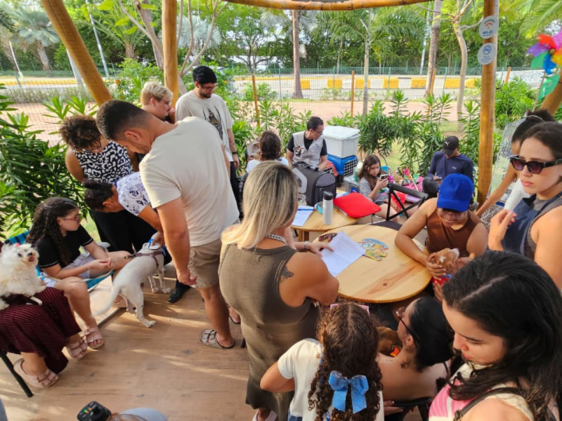 Pessoas reunidas em torno de uma mesa, interagindo e preenchendo formulários, sugerindo a formalização do processo de adoção.