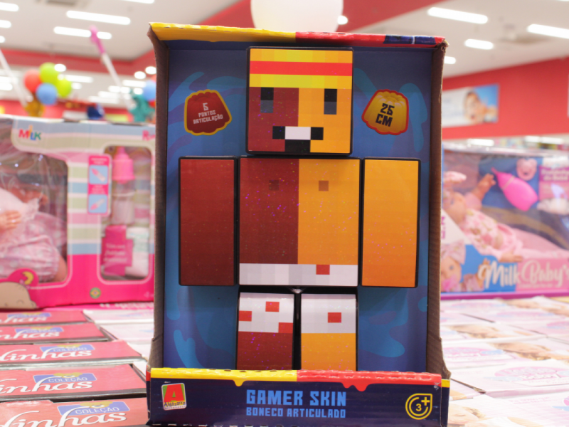 A imagem mostra um boneco articulado Gamer Skin da Minecraft na caixa, com um estilo pixelado.