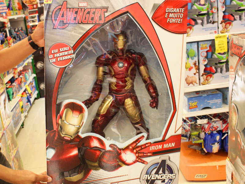 A imagem mostra um boneco grande do Homem de Ferro dos Vingadores da Marvel na caixa, sendo segurado em uma loja de brinquedos.
