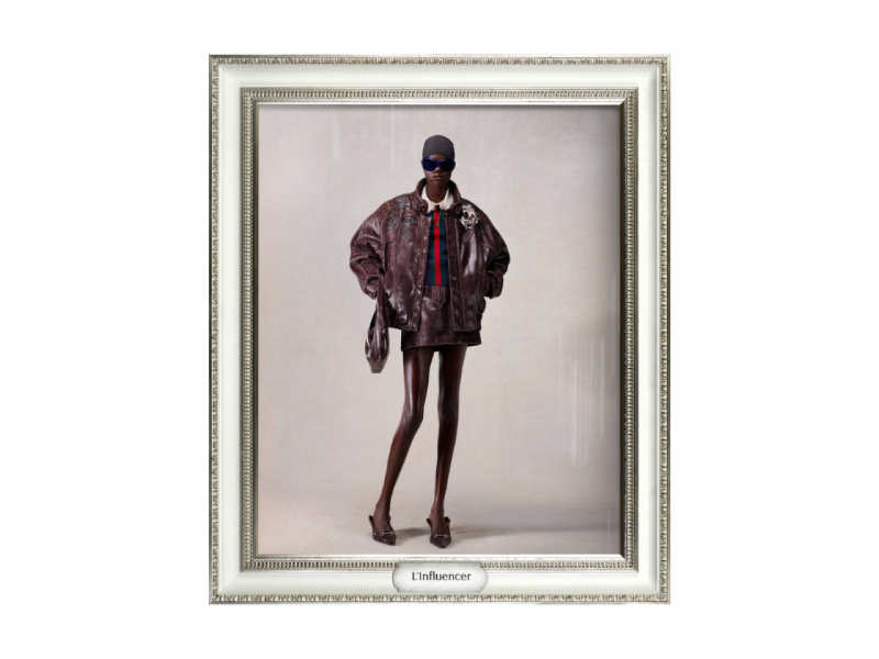 A imagem mostra um look L'influencer da nova coleção da Gucci, destacando uma jaqueta de couro oversized sobre mini-saia, boné e salto alto.  