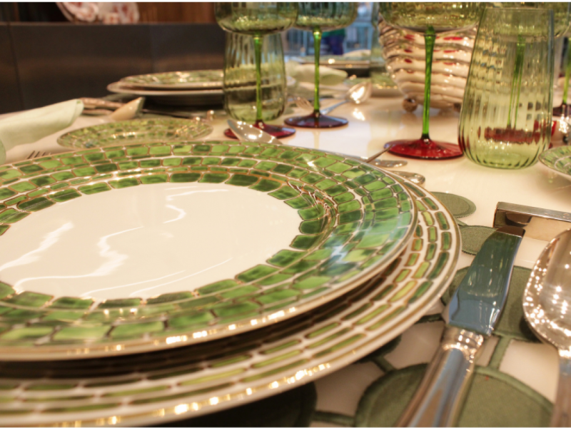 A imagem mostra um prato raso da Coleção Jade em verde e branco em primeiro plano, destacando os detalhes em mosaico e a borda dourada. A imagem mostra um prato raso da Coleção Jade em verde e branco em primeiro plano, destacando os detalhes em mosaico e a borda dourada.