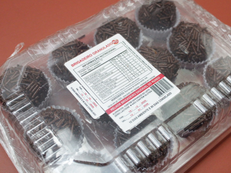 A imagem mostra uma caixa com vários brigadeiros granulados saudáveis sabor cacau A imagem mostra uma caixa com vários brigadeiros granulados saudáveis sabor cacau