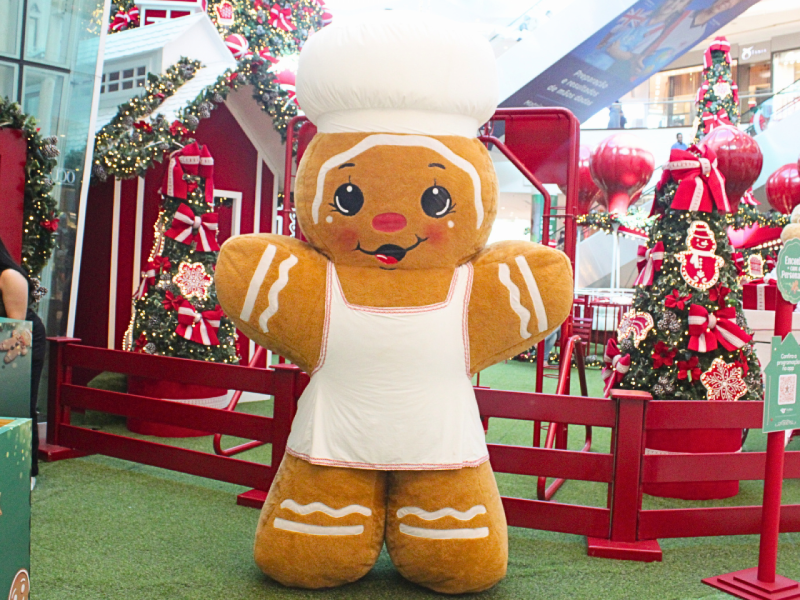 A imagem mostra um Biscoito de Gengibre com roupa de Chef de Cozinha em um cenário natalino vermelho.