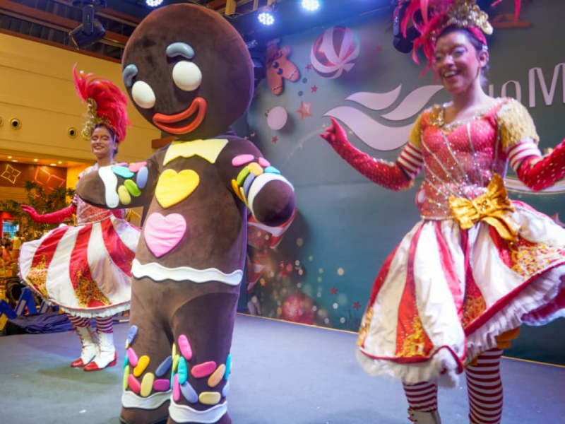 O personagem Biscoito de Gengibre e duas artistas em trajes temáticos se apresentando em um palco.