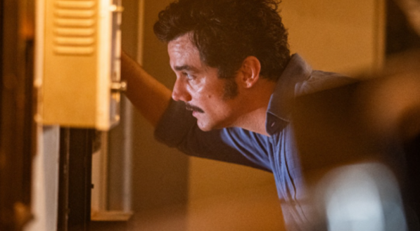 A imagem mostra um homem (Wagner Moura) de perfil olhando através de uma janela 