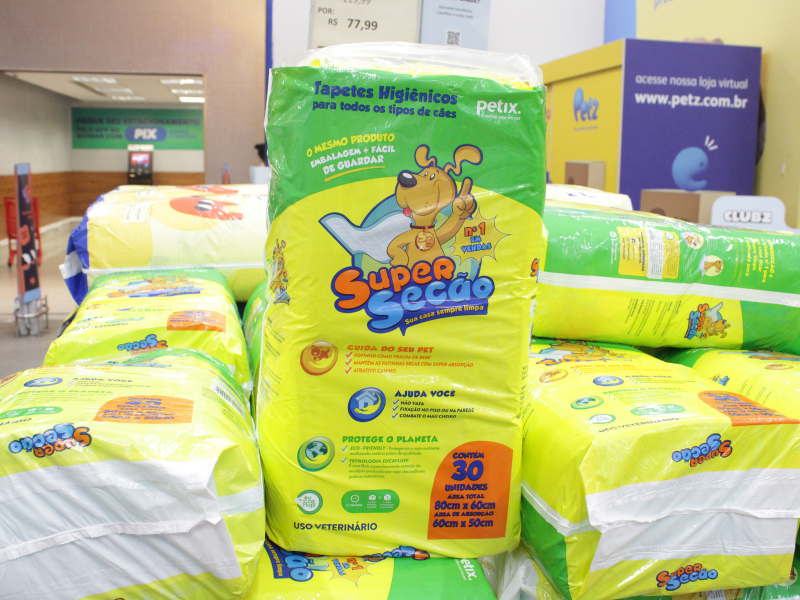 Pacote grande de tapetes higiênicos para cães (Petix – Super Secão) em destaque, com embalagem verde e amarela e ilustração de um cão com capa de herói.