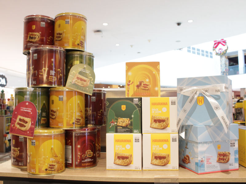 Exposição de latas e caixas de Panetone da marca Havanna, a maioria na cor amarela ou vermelha, destacando o sabor 