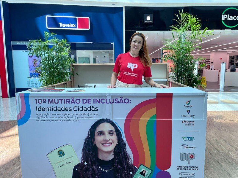 Balcão de informações que está localizado no Piso L1, próximo a Americanas e a atendente que é uma mulher branca, ruiva, com camisa vermelha do Ministério Público. 