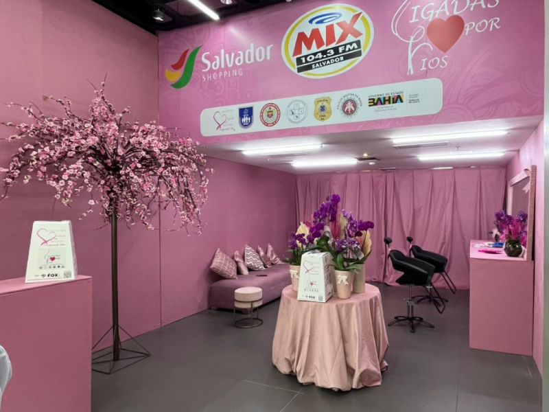 Parte interna da loja Outubro Rosa com as cadeiras onde serão feitos os cortes, mesa decorativa.