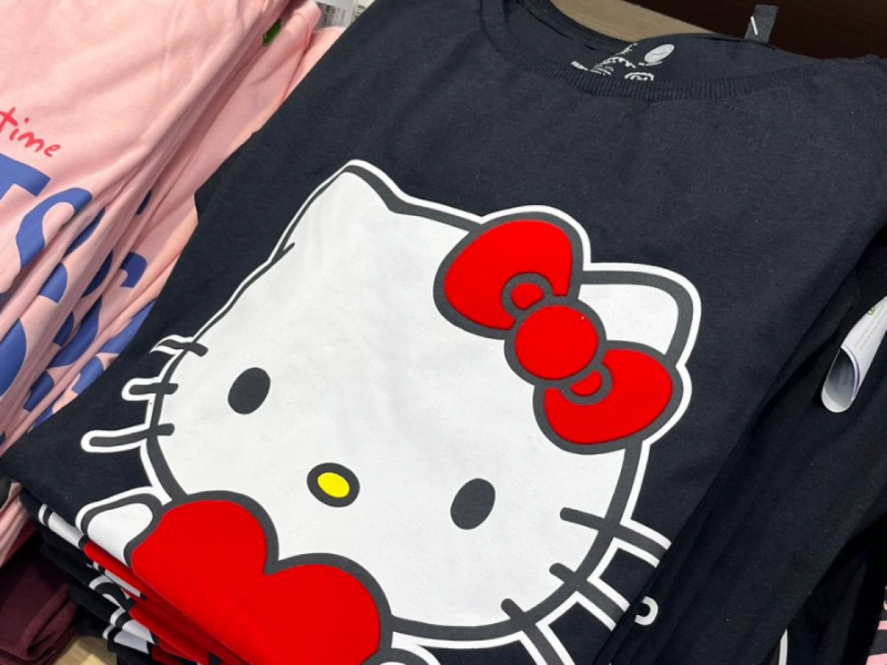 camisa dobrada, de cor preta e estampa da hello kit centralizada em tamanho grande.