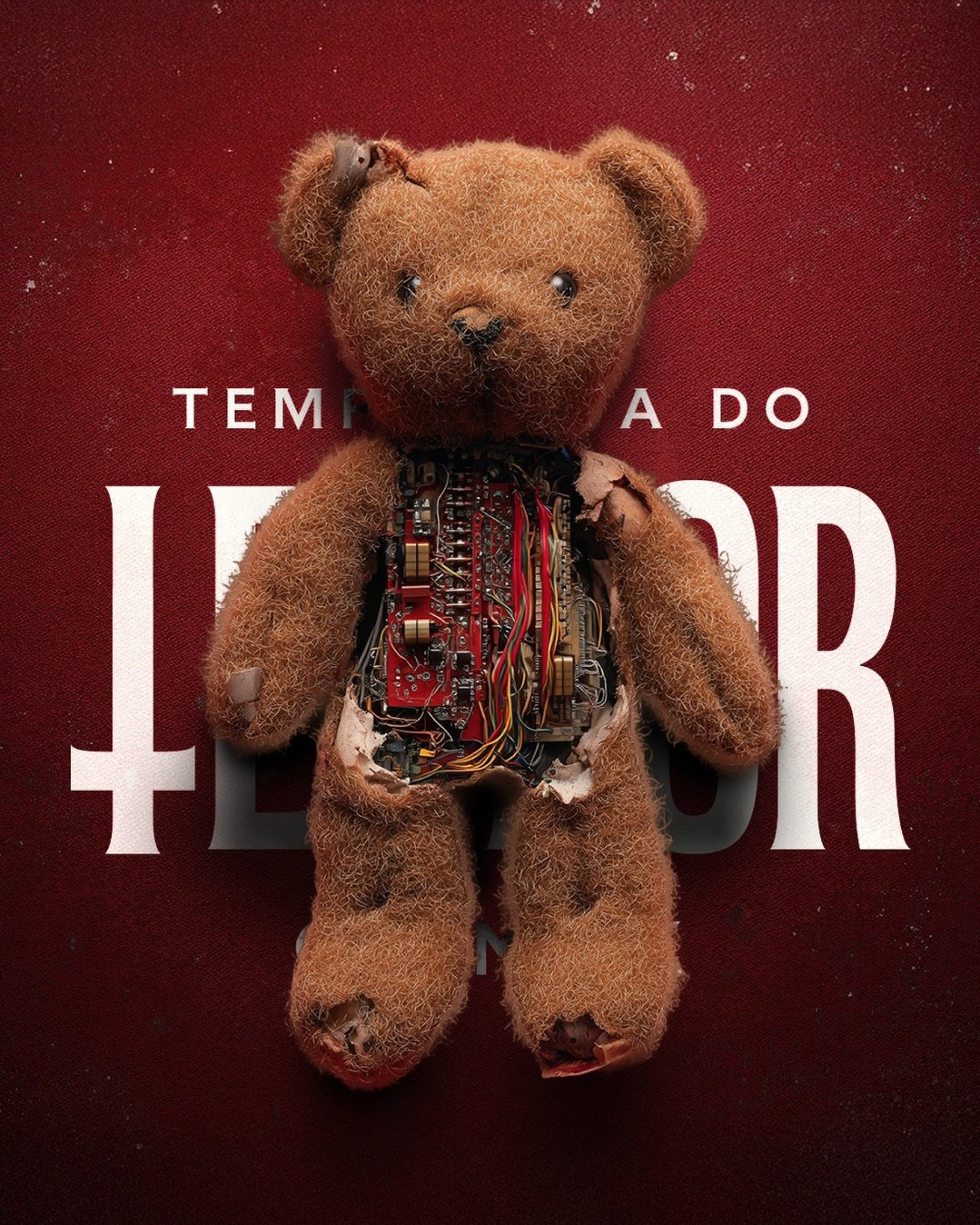 Fundo vermelho com um urso de pelúcia com a barriga à mostra, vemos fios e um dispositivo digital. 