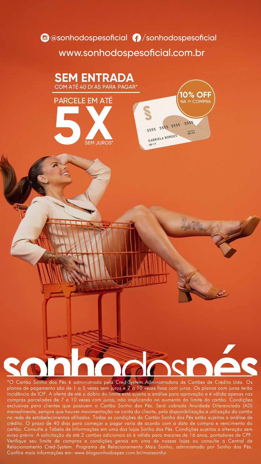 Mulher sorridente reclinada dentro de um carrinho de compras laranja, em um fundo plano da mesma cor. Ela usa roupa bege e sandálias de salto médio. No topo da imagem aparecem ícones de redes sociais e o site da marca Sonho dos Pés. Há textos promocionais: ‘Sem entrada com até 40 dias para pagar’, ‘Parcele em até 5x sem juros’ e um selo de ‘10% off na primeira compra’. Na parte inferior, há texto legal e informações sobre o cartão da loja.