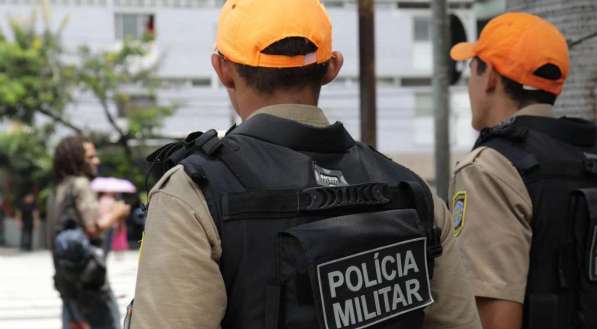 Dois policiais militares de farda e boné laranja