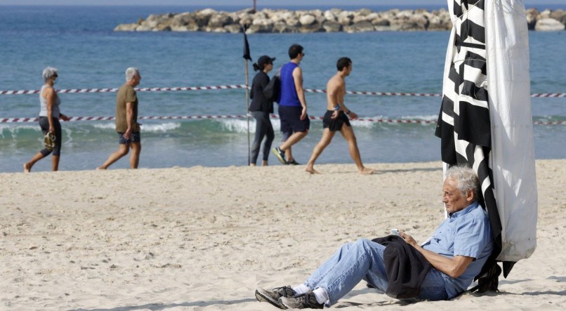 Idoso sentado na praia em Tel Aviv, Israel