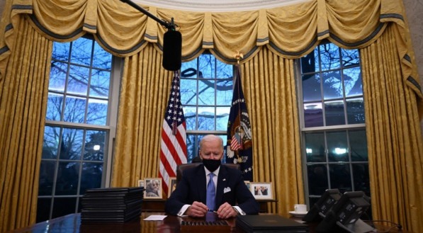 O presidente dos Estados Unidos, Joe Biden, segura uma caneta enquanto se prepara para assinar uma s&eacute;rie de ordens no Sal&atilde;o Oval da Casa Branca em Washington