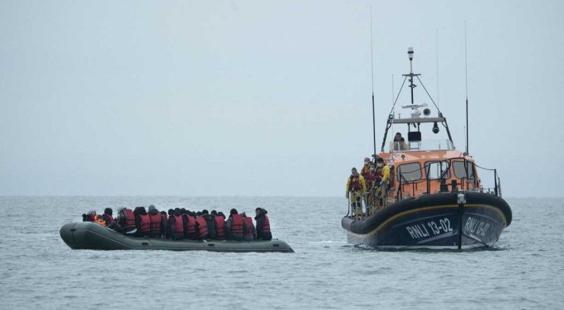 Os migrantes recebem ajuda do barco salva-vidas RNLI (Royal National Lifeboat Institution) antes de serem conduzidos a uma praia em Dungeness, na costa sudeste da Inglaterra