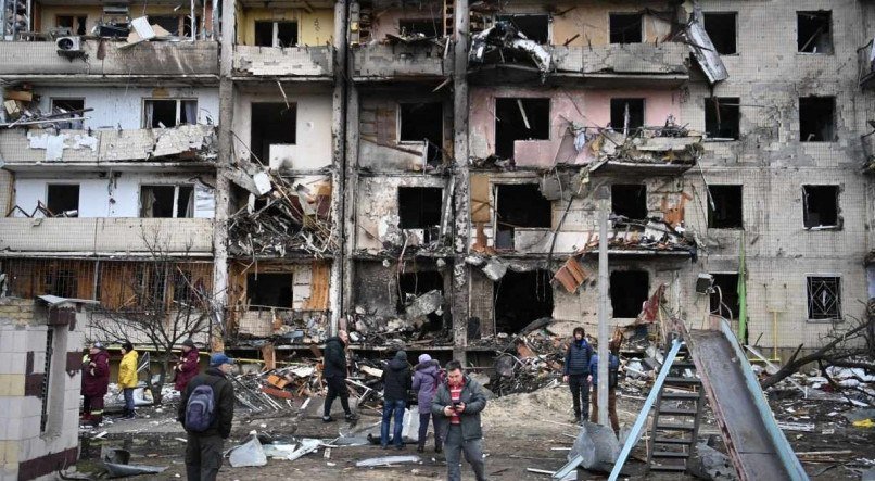 Pessoas se reúnem em frente a um prédio residencial bombardeado em Kiev