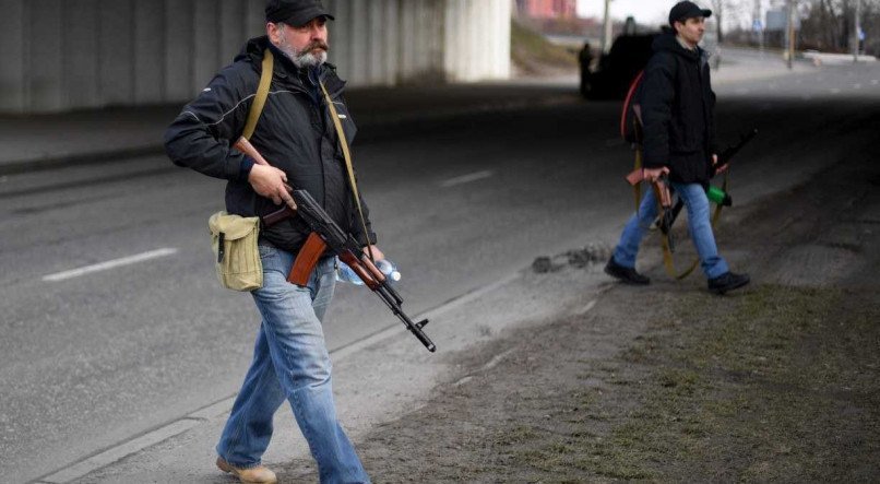 Voluntários com riffles AK-47 em estrada que leva para Kiev