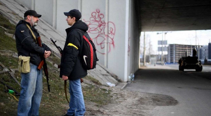 ARMAMENTO Voluntários com riffles AK-47 em estrada que leva para Kiev. Armas são distribuídas em escritórios de alistamento militar e civis usam braçadeira amarela para se reconhecerem