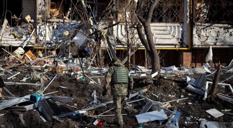 ESTÃO NA MIRA Soldado da Ucrânia observa prédio atacado por mísseis da Rússia; áreas residenciais de Kiev estão sendo atacadas enquanto invasores aumentam cerco à capital