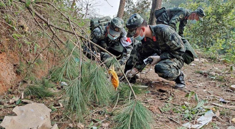 Militares chineses fazem busca na área em que o avião caiu