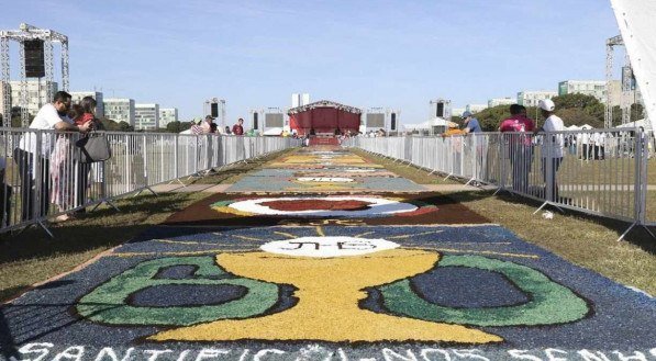 Fiéis confeccionam tapetes coloridos e artísticos feitos de serragem, sal, flores e outros materiais para celebrar Corpus Christi