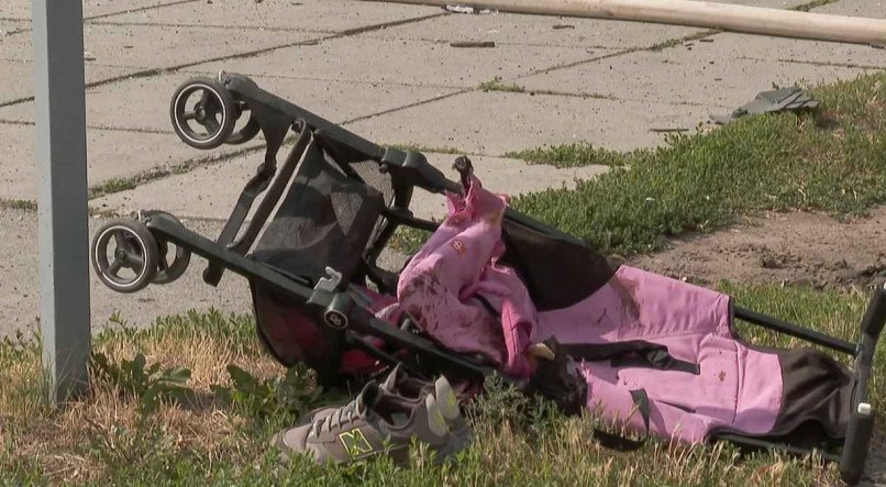 O carrinho rosa permanece tombado na rua e manchado com o sangue da menina