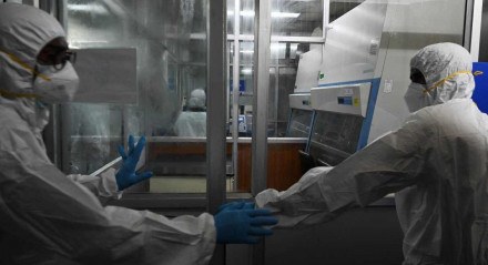 Técnicos com equipamentos de proteção em laboratório utilizado para testes de varíola dos macacos