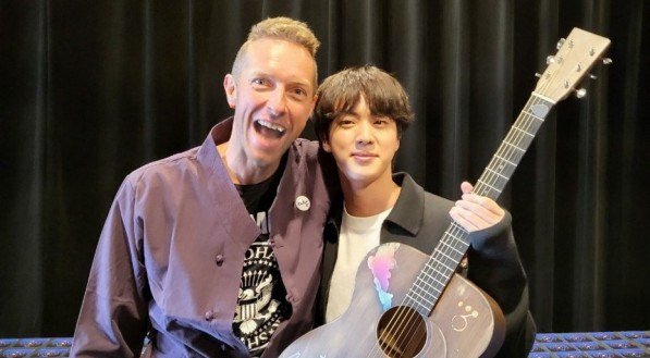 Chris Martin do Coldplay e Jin do BTS posam juntos. 