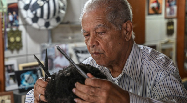O barbeiro João Araújo, conhecido como Didi, que cortou o cabelo da lenda do futebol brasileiro Pelé, trabalha em seu salão, em Santos