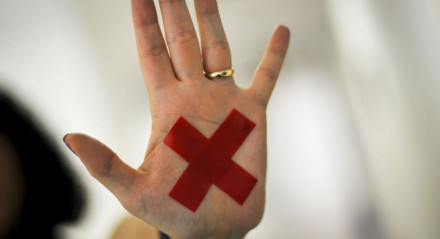 O sinal "X" feito com batom vermelho (ou qualquer outro material) na palma da mão ou em um pedaço de papel, o que for mais fácil, permite que a pessoa treinada reconheça que aquela mulher foi vítima de violência doméstica e, assim, acione a Polícia Militar.