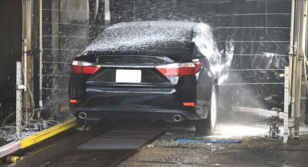Carro preto passando por um lava-jato
