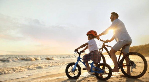 Pai e filho andando de bicicleta na praia